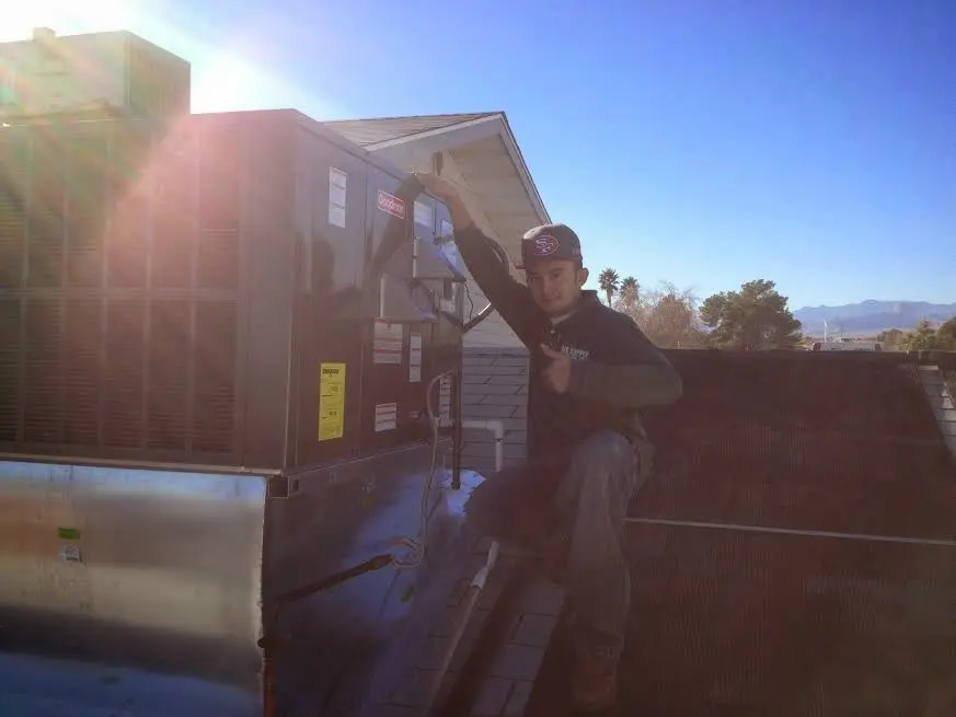 HVAC technician performing AC Tune-Up on a rooftop unit in Beaumont